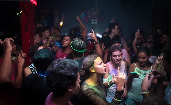 Lively nightclub scene with a vibrant crowd dancing energetically under colorful lights.